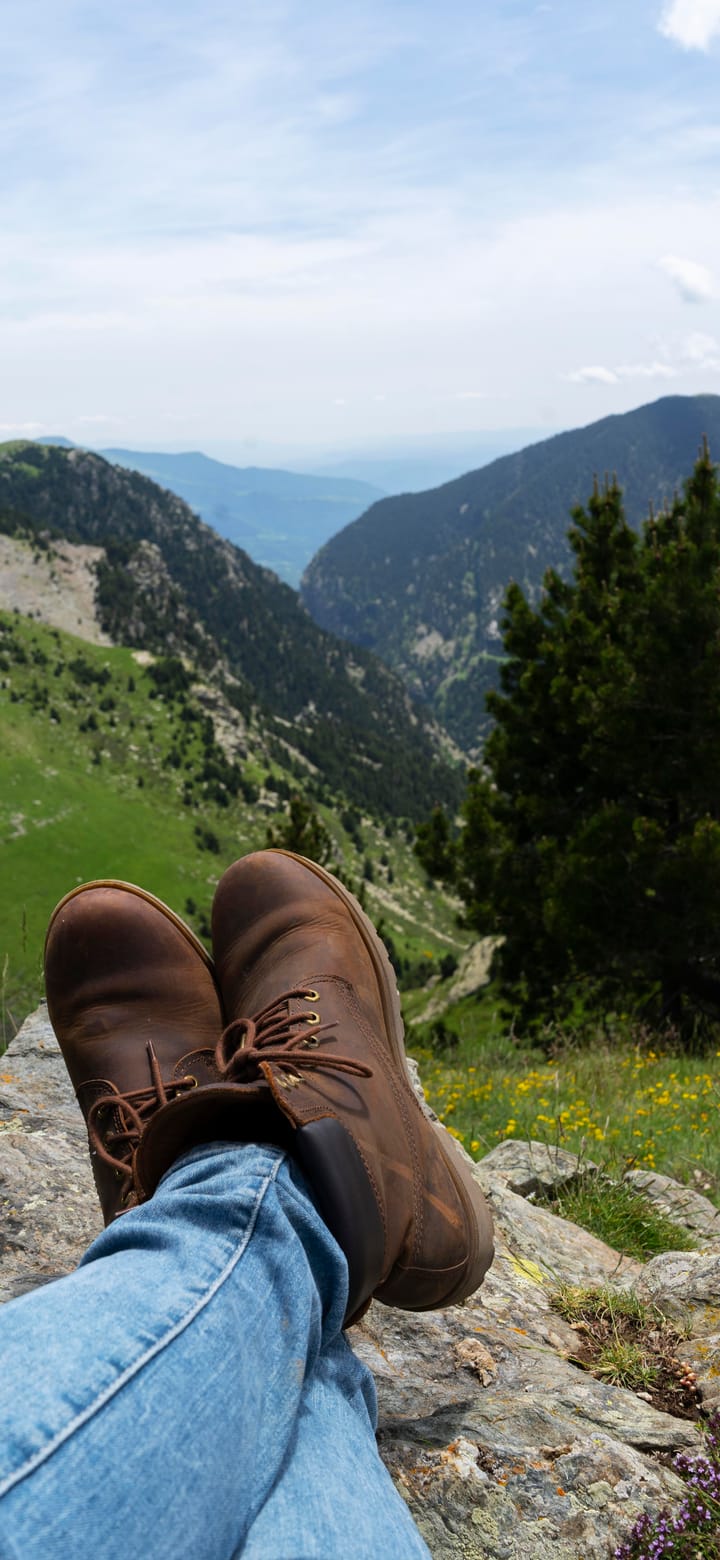 Outstretched legs on a rock, a wide mountain valley beyond.